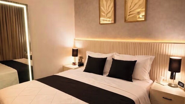 A hotel room with a large bed, bedside tables, a wall-mounted lamp, and two framed artworks. - 5 Estrelas - Alto do Bueno (Goiânia)