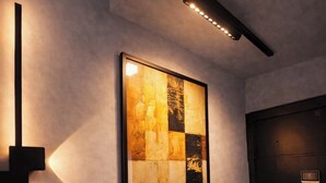 A hallway with a framed artwork on the wall, a black door, and a light fixture on the ceiling. - 5 Estrelas - Alto do Bueno (Goiânia)