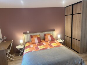 Een slaapkamer met een bed, nachtkastjes, een bureau en een kledingkast.