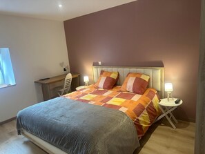 Een slaapkamer met een bed, nachtkastjes, een bureau en een stoel.