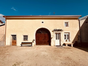 Ein Gebäude mit einer großen Holztür, einem Bogenportal und einem kleinen Fenster auf der rechten Seite.