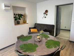 Ein stilvolles Wohnzimmer mit einem runden Tisch, einer Couch und einer Topfpflanze.