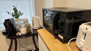 Una cocina con cafetera, microondas, tostadora y una pequeña mesa con frascos.