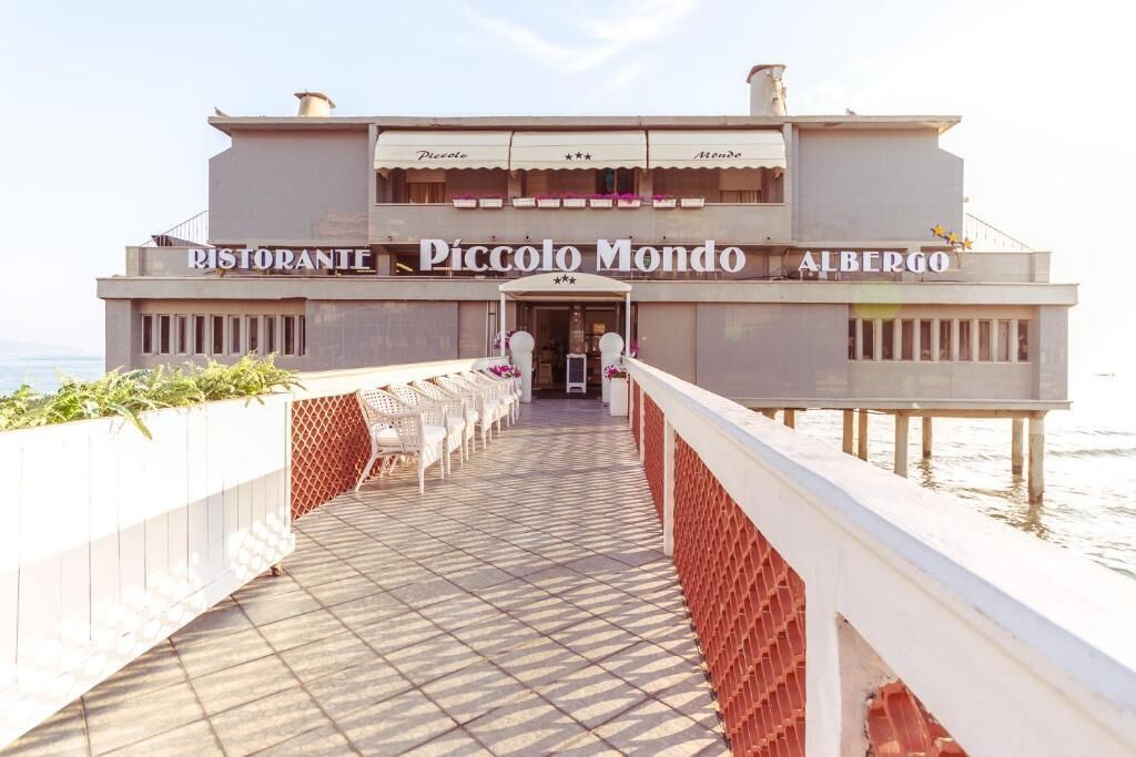 A waterfront restaurant named Piccolo Mondo with outdoor seating and a view of the sea.
