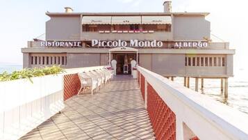 A waterfront restaurant named Piccolo Mondo with outdoor seating and a view of the sea.