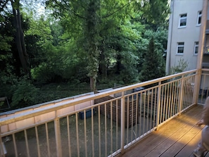 Ein Balkon mit Metallgeländer, der auf einen dichten Wald blickt.