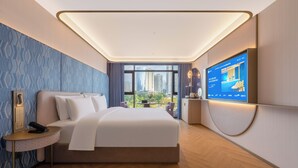 Una habitación de hotel moderna con una cama grande, televisión y vistas a la ciudad.