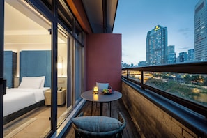 A hotel room with a balcony, a bed, a table with a fruit bowl, and a city view. - Manxin Hotel Chengdu Taikoo Li JiuyanBridge (Chengdu)