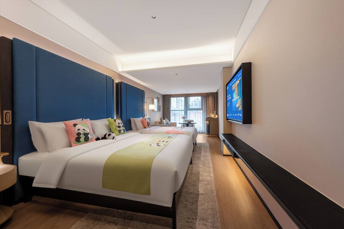 A hotel room with a large bed, a desk, a TV, and a window.