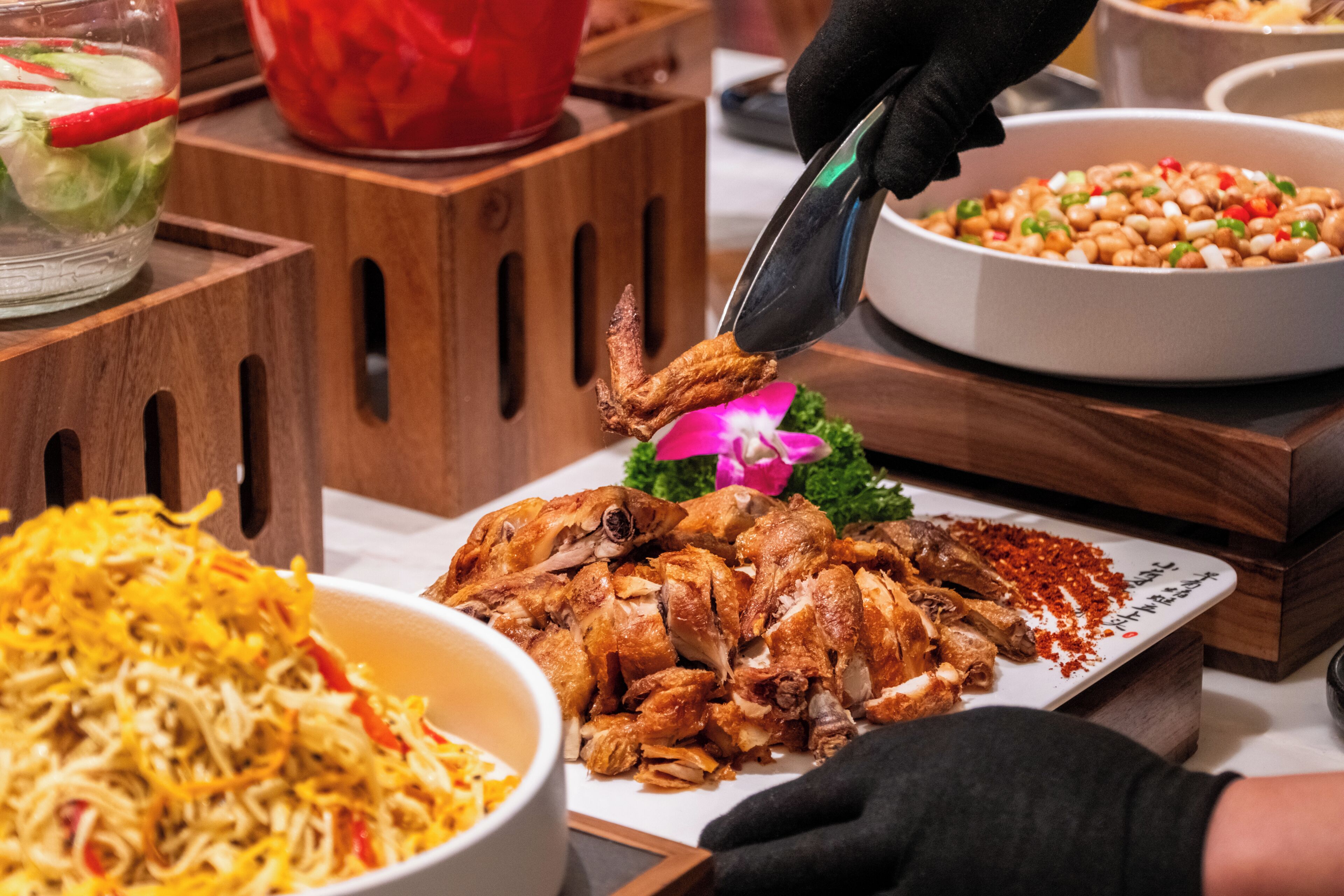 A buffet with various dishes including a plate of sliced meat, a bowl of noodles, and a container of beans.