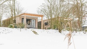 Een modern huis met een houten gevel, een overdekte veranda en een trap naar de ingang.