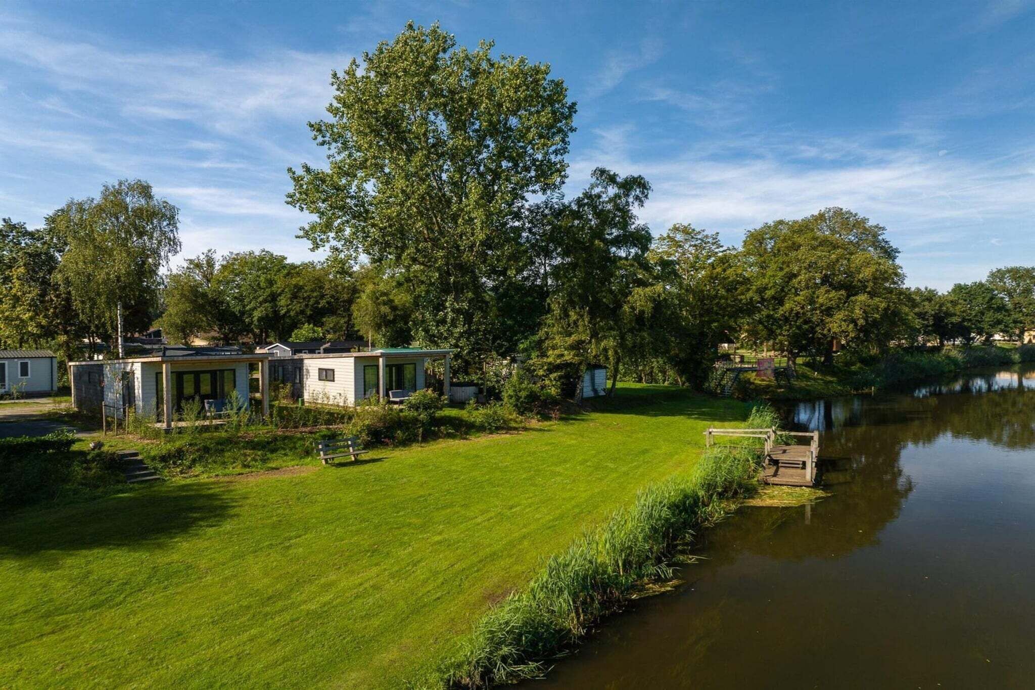 A lakeside property with a grassy lawn, a dock, and several small buildings.