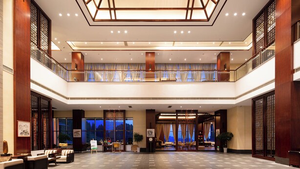 A spacious lobby with a high ceiling, a seating area, and a view of the outdoors. - Howard Johnson Lushan Jiahao (Jiujiang)