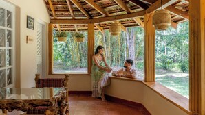 A room with a wooden ceiling, large windows, and a view of the outdoors. - Coffee Cottage by Raho Stream View Estate Escape (Coorg)
