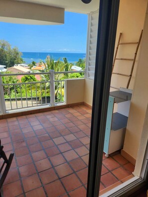 Ein Balkon mit gefliestem Boden, Blick auf den Ozean und eine an der Wand stehende Leiter.