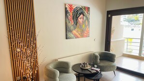 Un soggiorno moderno con due poltrone, un tavolino, un pannello decorativo e un'ampia finestra.