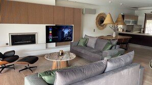 Un soggiorno moderno con televisore a schermo piatto, camino, zona pranzo e cucina.