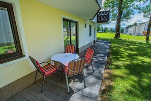 Eine Terrasse mit Tisch und Stühlen, ein überdachter Bereich und Blick auf eine Wohngegend.