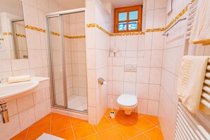 Ein Badezimmer mit Dusche, Toilette, Waschbecken und einem Fenster.