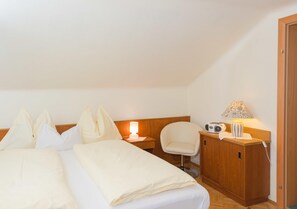 Een hotelkamer met een bed, bedlamp, stoel, houten kast en een radio.