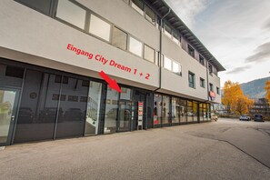 Ein Gebäude mit einem Schild, auf dem 'Eingang City Dream 1 + 2' steht, und einem roten Pfeil, der zum Eingang zeigt.