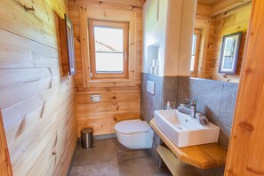 Ein Badezimmer einer Holzhütte mit Toilette, Waschbecken und Fenster.