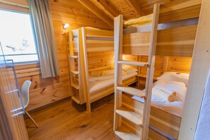 Eine Holzhütte mit Etagenbetten, einem Sessel und einem Fenster mit Vorhängen.