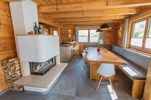 Ein Holzblockhaus im Inneren mit Essbereich, Kamin und Küche.