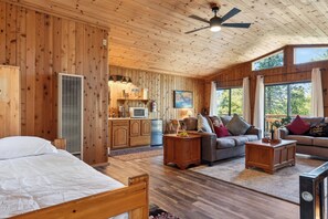 L'intérieur d'un chalet en bois, avec un lit, un canapé et un coin repas.