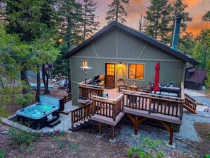 Eine Hütte mit Terrasse, Whirlpool und Sitzgelegenheit im Freien.