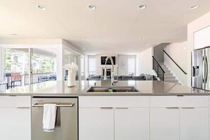 A modern kitchen with a central island, a built-in sink, and a view to a living area. - PO3: Spacious 4-bedroom house in lovely Port Orchard with central AC (Port Orchard)