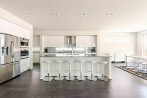 A modern kitchen with a central island, bar stools, and stainless steel appliances.