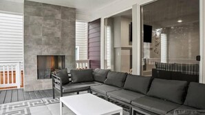 Una sala de estar moderna con un sofá modular, una chimenea y ventanas amplias.