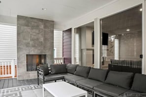 A modern living room with a sectional sofa, a fireplace, and large windows.