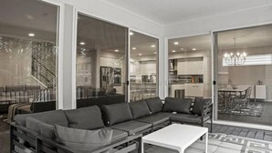 Una sala de estar moderna con un sofá seccional, una mesa de centro y amplias puertas correderas de vidrio que dan a un balcón.