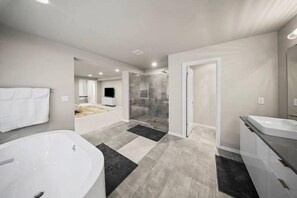 Une salle de bain moderne dotée d’une grande baignoire, d’un espace douche et d’un meuble-lavabo avec un miroir.