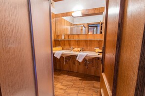 Ein Badezimmer mit Holzwänden, Fliesenboden, zwei Waschbecken und Handtüchern auf der Ablagefläche.