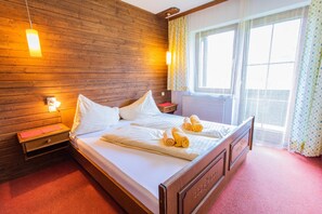 Ein Zimmer mit Holzwänden, einem Bett, Nachttischen und einem fenster mit Vorhängen.