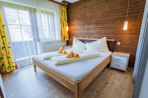 Een kamer met houten lambrisering, een bed, nachtkastjes en een raam met gordijnen.