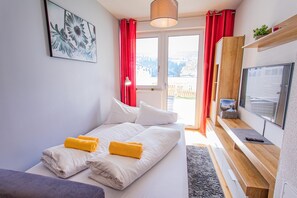 Ein Schlafzimmer mit einem Bett, einem Fernseher und einem Fenster mit Vorhängen.