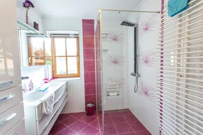 Ein Badezimmer mit Dusche, Waschbecken, Spiegel und Fenster.