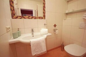 Ein Badezimmer mit Waschbecken, Spiegel, Toilette und einem Ablagefach für Toilettenartikel.