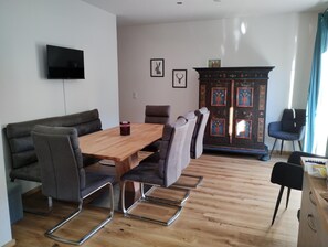 Ein modernes Wohnzimmer mit einem Holzesstisch, grauen Sofas und einer Kommode mit dekorativen Paneelen.