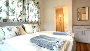 Ein Schlafzimmer mit Bett, Kissen, Dusche, Kleiderschrank und Spiegel.