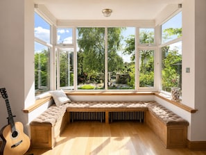 A room with a large bay window, a cushioned bench, a guitar, and a radiator. - Elegant Central St Andrews Home with Parking, Garden & Putting Green (St Andrews)