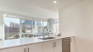 A modern kitchen with a large window, stainless steel sink, and a dishwasher. - Rooftop Pool + Spa + Sky Lounge | Little Italy + Bay Views | Ancora by AvantStay (San Diego)