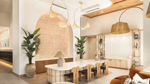 Um interior moderno com uma área de refeições central, móveis de madeira e plantas em vasos.