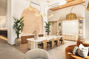 A modern interior with a central dining area, wooden furniture, and potted plants. - Rooftop Pool + Spa + Sky Lounge | Walkable San Diego's Little Italy | Ancora (San Diego)