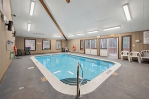 A swimming pool with a lifeguard chair, a hot tub, and a view of the outdoors.