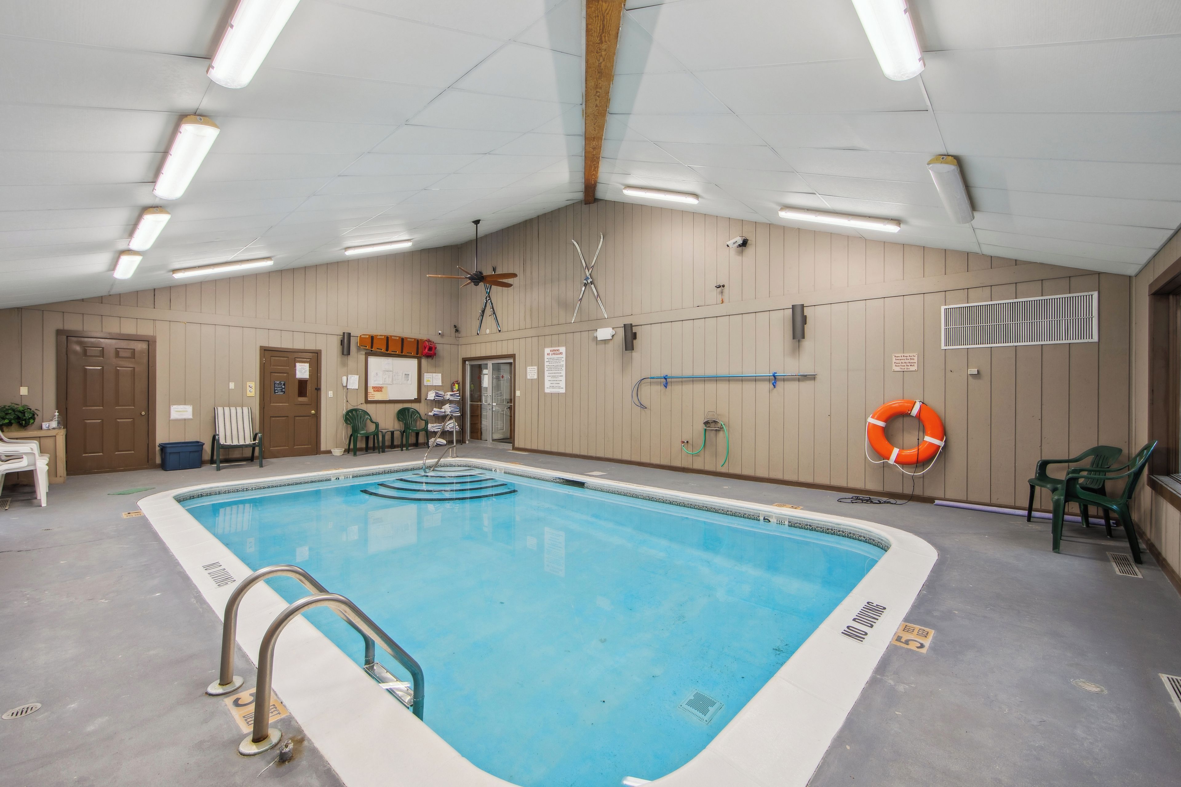 Una piscina interna con un galleggiante di salvataggio, una ventola a soffitto e una porta.